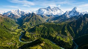 Panoramic view of Nepal's diverse landscape, featuring green valleys and the majestic Himalayas.